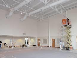 A spacious room featuring a high white ceiling and a ladder positioned against the wall.