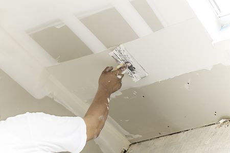 A man carefully installs a light fixture in a well-lit room, focusing on the task at hand.