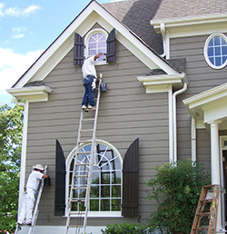 Two men painting the exterior of a house, showcasing teamwork and home improvement efforts in progress