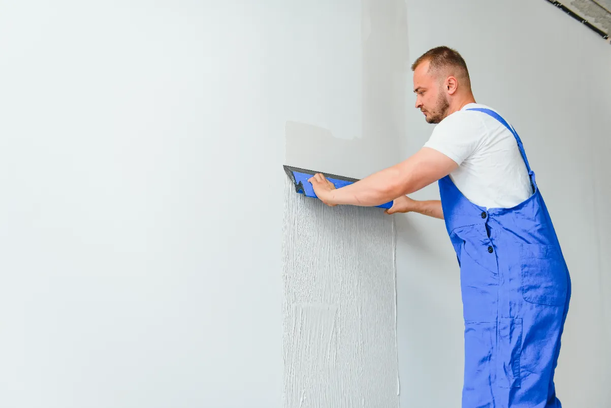 A worker drywall repairing the walls of the house.