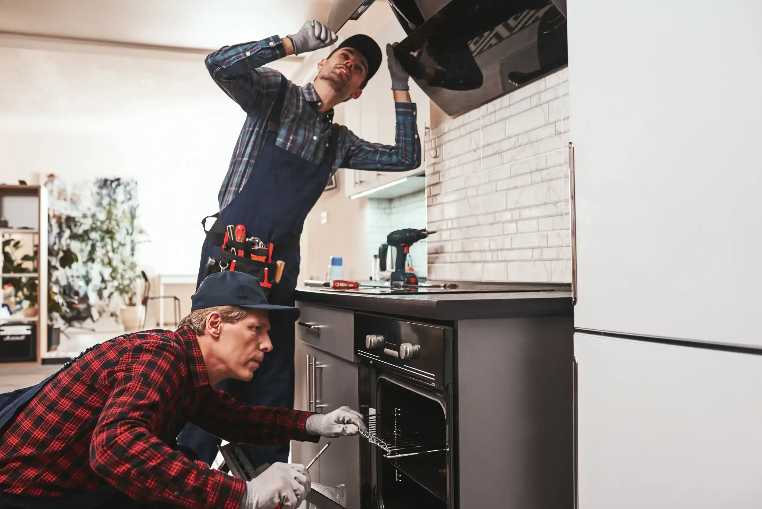 Two serviceman installing the new oven and exhaust.