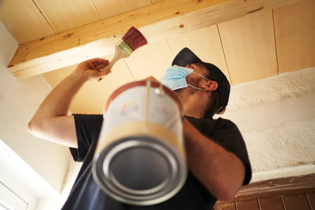 A man ready to paint the ceiling of the house.