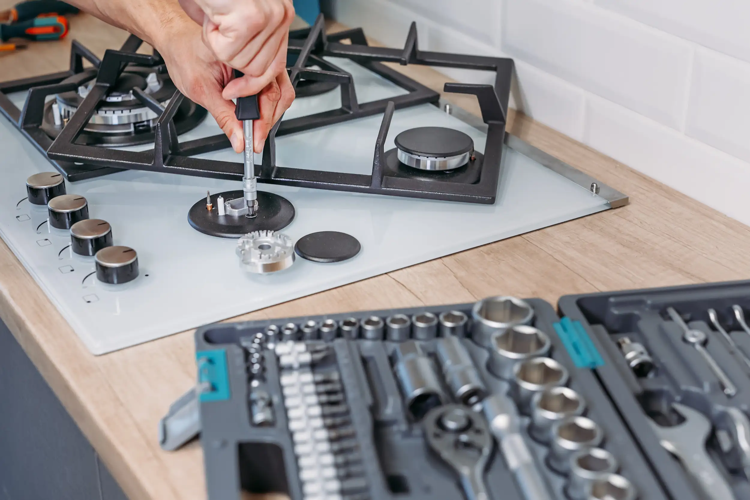 A close up of hand repairs the hotplate of a gas panel.