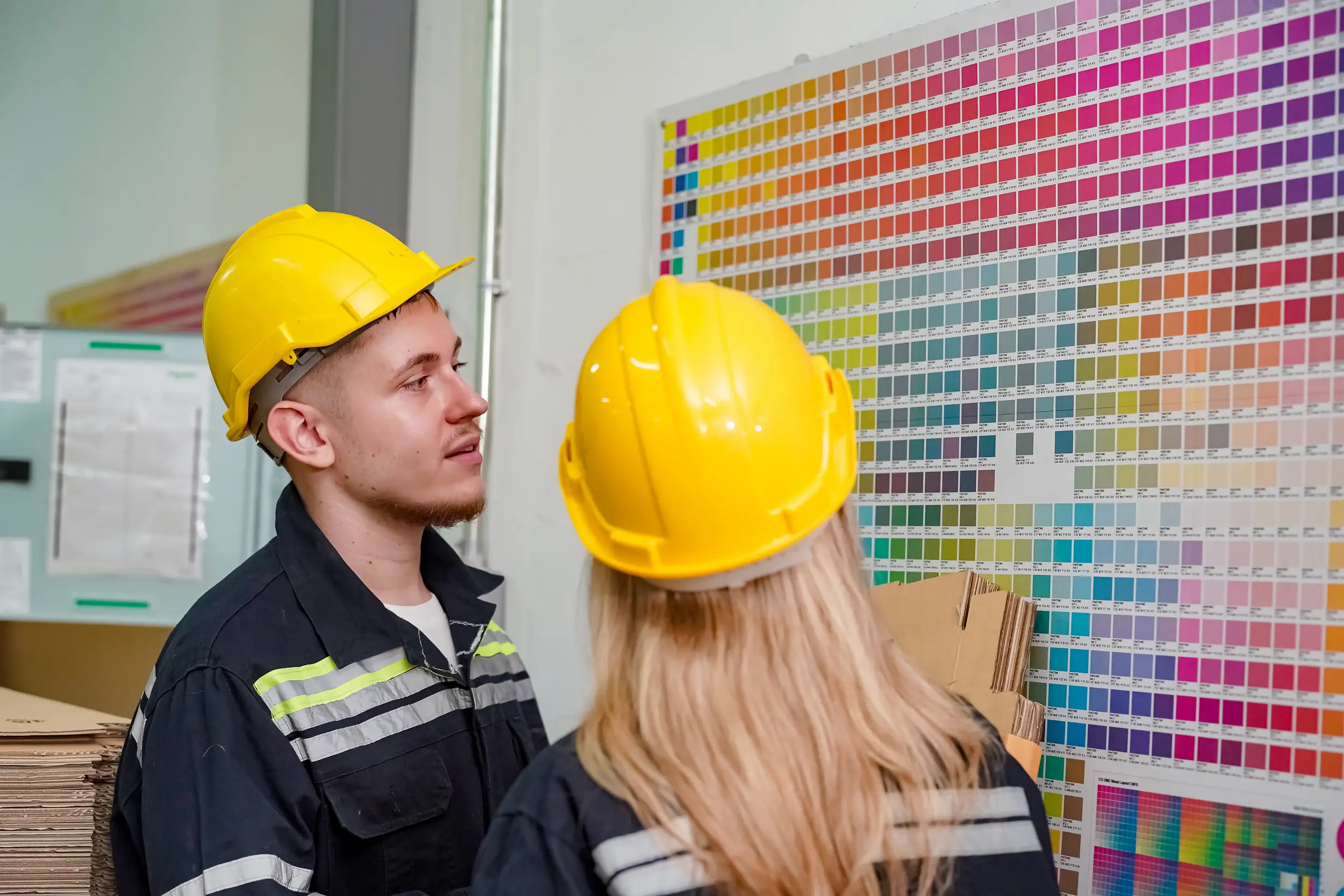 Two workers discussing the paint on the color palette chart.